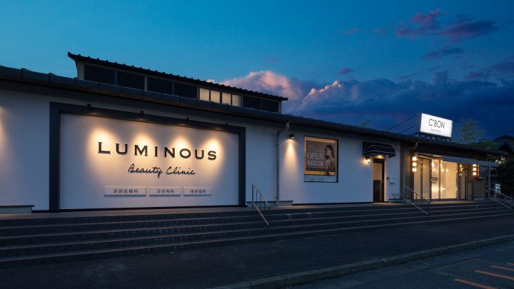 ルミナスビューティークリニック 群馬県太田市 美容クリニック 黒×白×大理石調・ホテルライク 外観。白い建物に院名サインと夜の照明（カエル・デザイン・プロジェクト株式会社）
