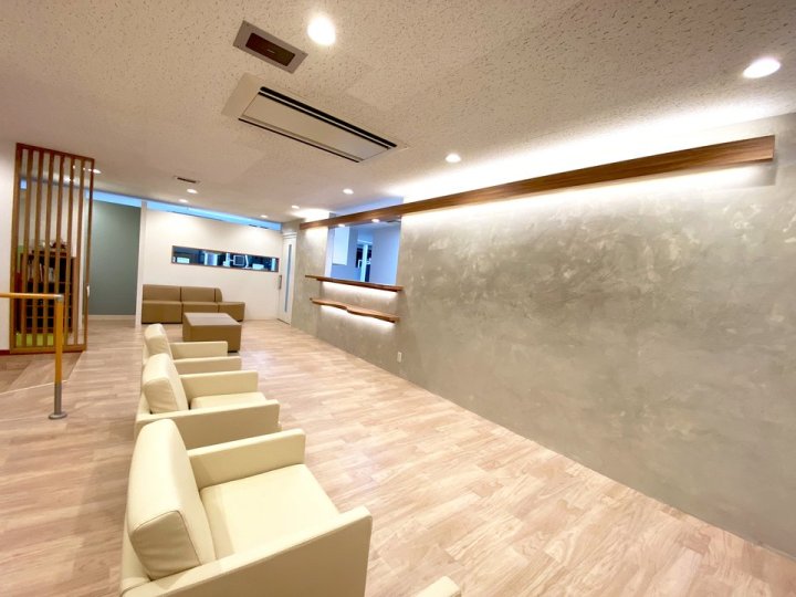 多摩市のクリニック 東京都多摩市 歯科クリニック 木目×グレー 待合の別角度。グレーの壁と木の縦格子、ベンチソファ（株式会社S plus Design’s）