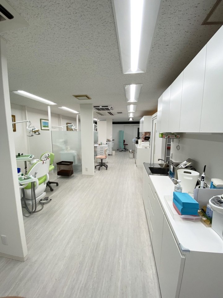 多摩市のクリニック 東京都多摩市 歯科クリニック 木目×グレー 診療室の通路。ユニットごとのパーテーションと白い収納・滅菌機器（株式会社S plus Design’s）