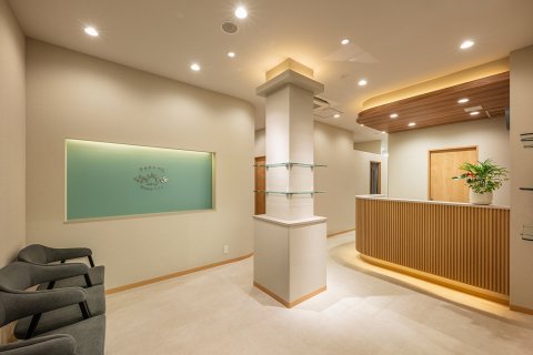 おおたかの森 Beauty clinic 千葉県 美容クリニック 白×木格子・ナチュラル 受付と待合。木格子のカウンターとグレーのソファ(サンリット建設(DESIGN STUDIO TEMPO))
