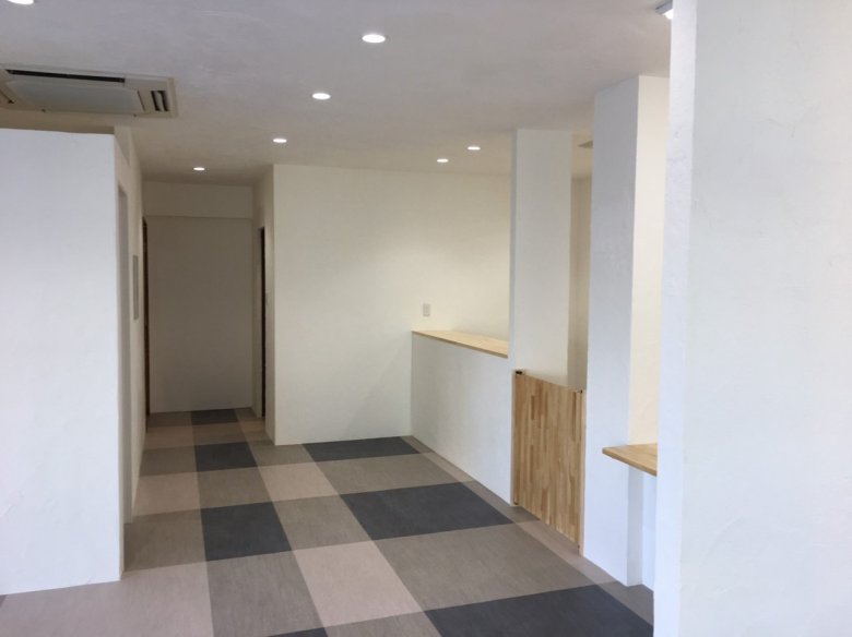 つつじ薬局 土気店（千葉県千葉市緑区）の完工時。白い内装と市松のタイル床、カウンター、什器搬入前（施工：株式会社ビリーフデザイン）