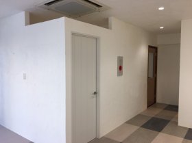 つつじ薬局 土気店（千葉県千葉市緑区）の完工時。白い壁と扉、奥へ続く廊下と市松のタイル床（施工：株式会社ビリーフデザイン）