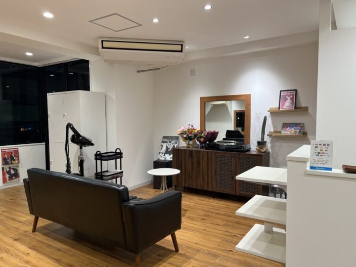 株式会社アンノーンの施工事例。白い壁とダウンライトの店内に黒いレザーのソファ、木の鏡台と収納棚、ディスプレイ棚、フローリングの床(株式会社アンノーン)