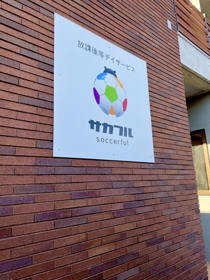 サカフル神戸北店 神戸市北区 放課後等デイサービスの外壁サイン。レンガ調の外壁にサッカーボールのロゴと「放課後等デイサービス サカフル」のサインパネル（LEBON DESIGN）