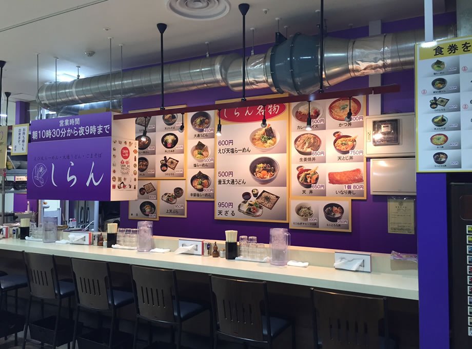 しらん（えび天しおらーめん）の内装（北海道・ラーメン店・カウンター上の露出ダクトと券売機の案内、メニュー掲示）