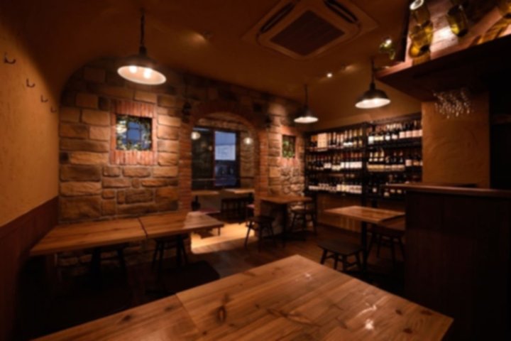 東京都の店舗内装工事 施工後。レンガ調の壁と木のテーブル席、ペンダント照明、奥にボトルを並べた棚がある飲食店（株式会社effort）