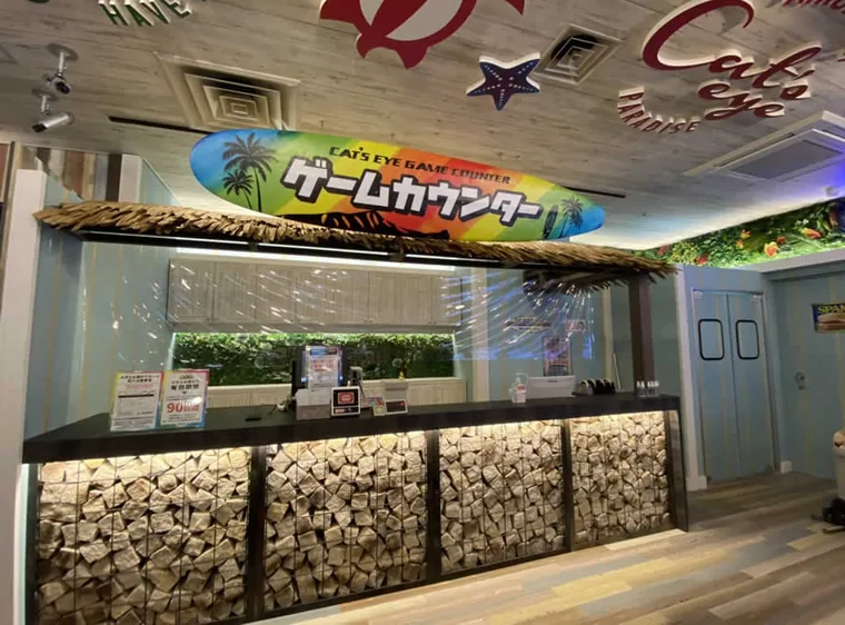 キャッツアイ東千葉店（千葉市・アミューズメント施設）。石を組み合わせた受付カウンターと、木目の床や天井を設けたゲームセンター。