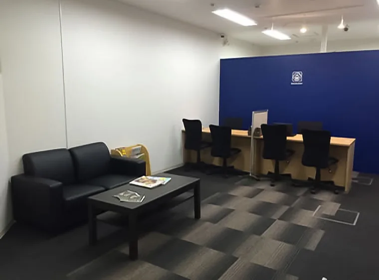 手前にソファとローテーブル、奥に対面カウンターを並べています。青い壁が接客エリアの背景になっています。