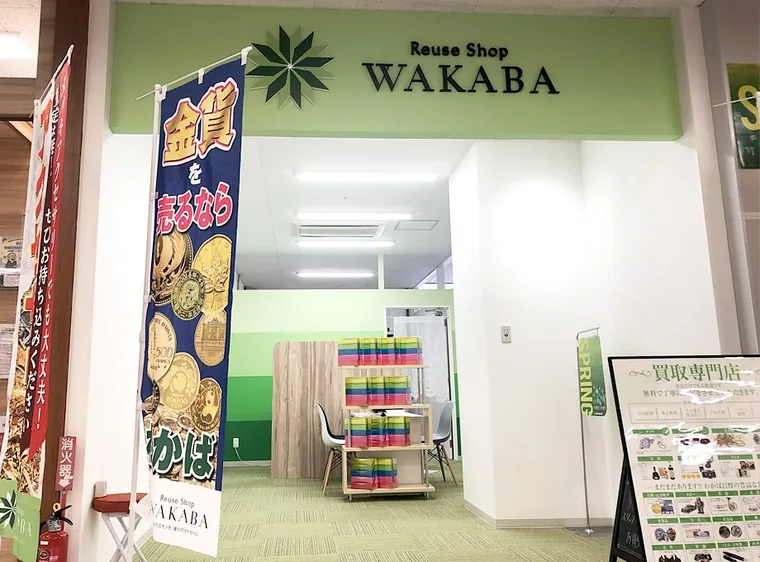 商業施設の通路に面した入口です。緑のサインを掲げ、奥の接客席まで白い壁とグリーンの床をつないでいます。