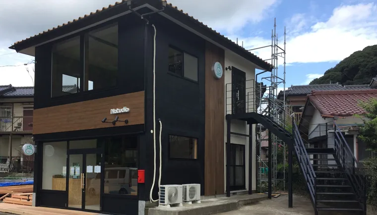 1階にカフェ、2階に英会話・ヨガ教室がある建物の外観。黒い外壁に木目を組み合わせています。