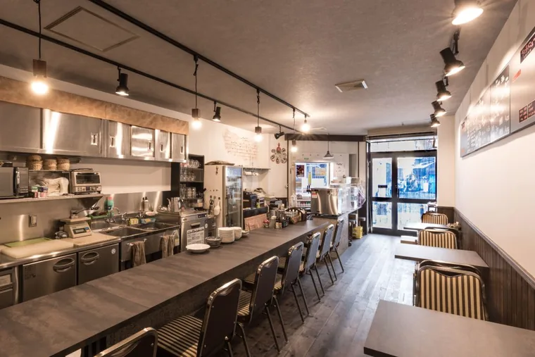 厨房に向かうカウンター席と壁側のテーブル席。通路は店の入口までつながっています。