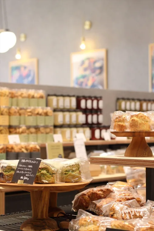 包装された商品を高さの異なる台に並べています。木の平台とケーキスタンドを組み合わせ、商品名を添えた陳列です。