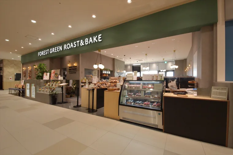 手前にガラスのショーケース、中央に商品を並べる什器を配置しています。奥には客席が続き、販売スペースとの位置関係が見えます。