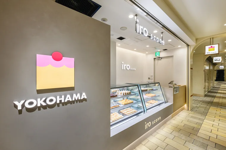通路に面してショーケースを配置し、横の壁に店舗のシンボルを設けています。店頭の開口部から商品とレジの位置が見えます。